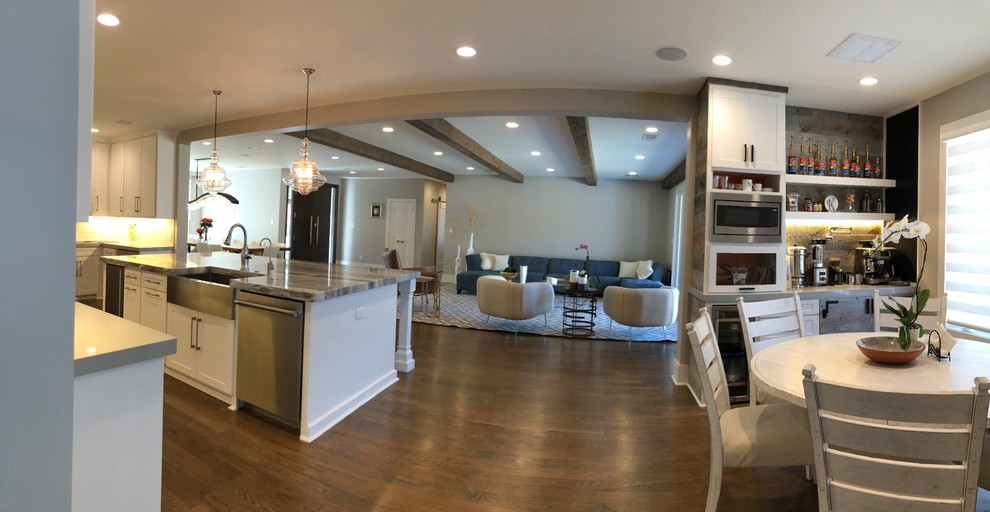Inspiration for a large transitional l-shaped medium tone wood floor and brown floor open concept kitchen remodel in Dallas with an undermount sink, shaker cabinets, white cabinets, quartz countertops, gray backsplash, ceramic backsplash, stainless steel appliances and an island