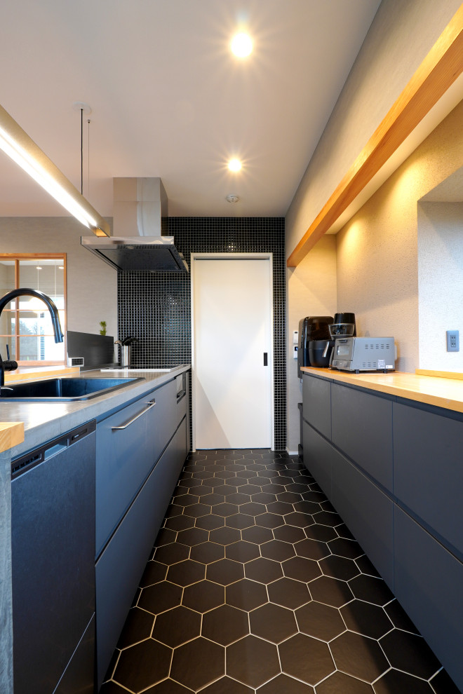 This is an example of a galley open plan kitchen in Tokyo Suburbs with a drop-in sink, flat-panel cabinets, grey cabinets, concrete benchtops, black splashback, mosaic tile splashback, ceramic floors, with island, black floor, beige benchtop and wallpaper.