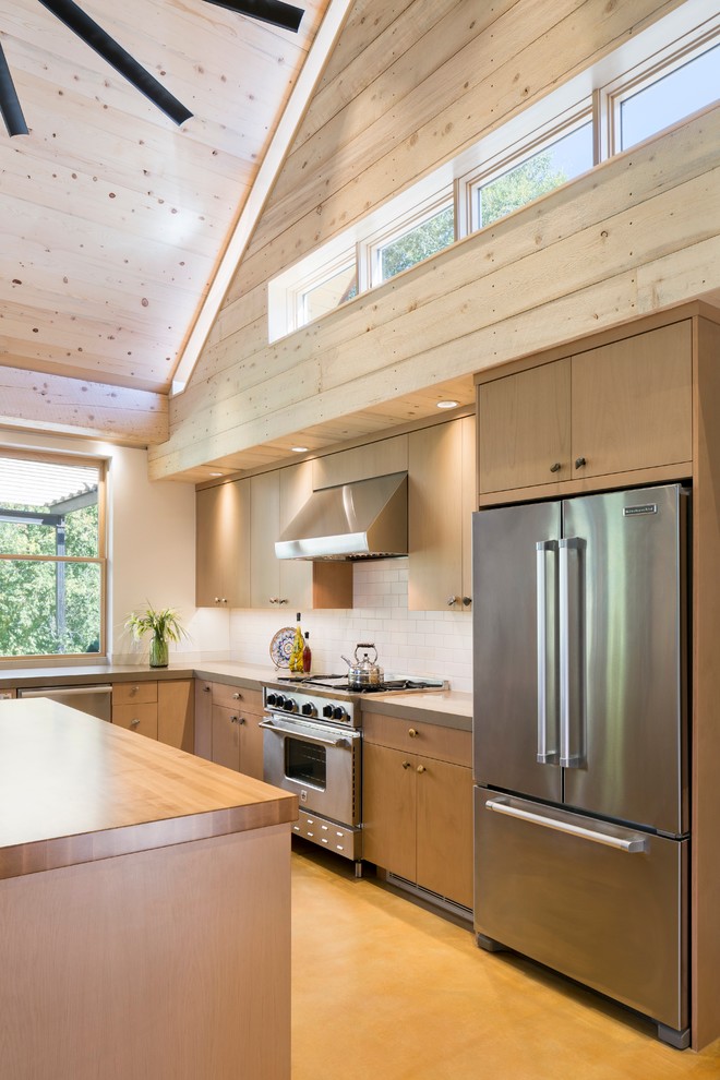 Design ideas for a mid-sized country l-shaped eat-in kitchen in Denver with an undermount sink, flat-panel cabinets, light wood cabinets, wood benchtops, beige splashback, ceramic splashback, stainless steel appliances, light hardwood floors and with island.