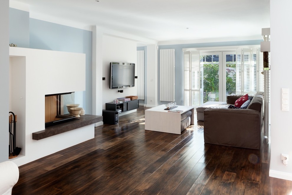 Inspiration for a contemporary family room in Hamburg with blue walls, dark hardwood floors, a corner fireplace and a plaster fireplace surround.