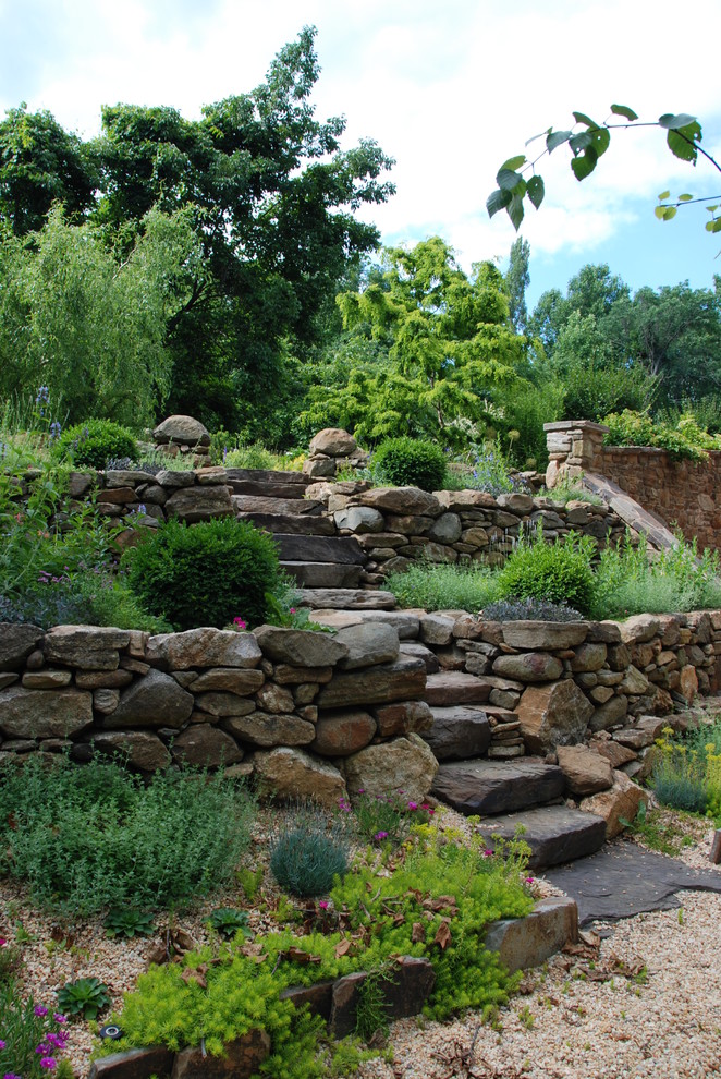 This is an example of a small drought-tolerant and partial sun backyard stone retaining wall landscape in Philadelphia for spring.
