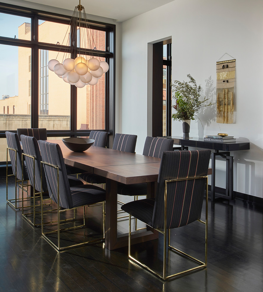 This is an example of a contemporary dining room in Chicago with white walls, dark hardwood floors and brown floor.