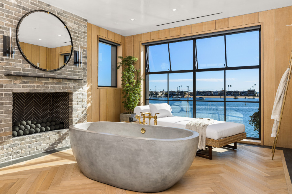 Inspiration for a beach style bathroom with a freestanding tub, brown walls, light hardwood floors, beige floor and wood walls.