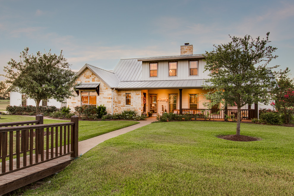 This is an example of a large traditional two-storey beige exterior in Houston with stone veneer and a gable roof.