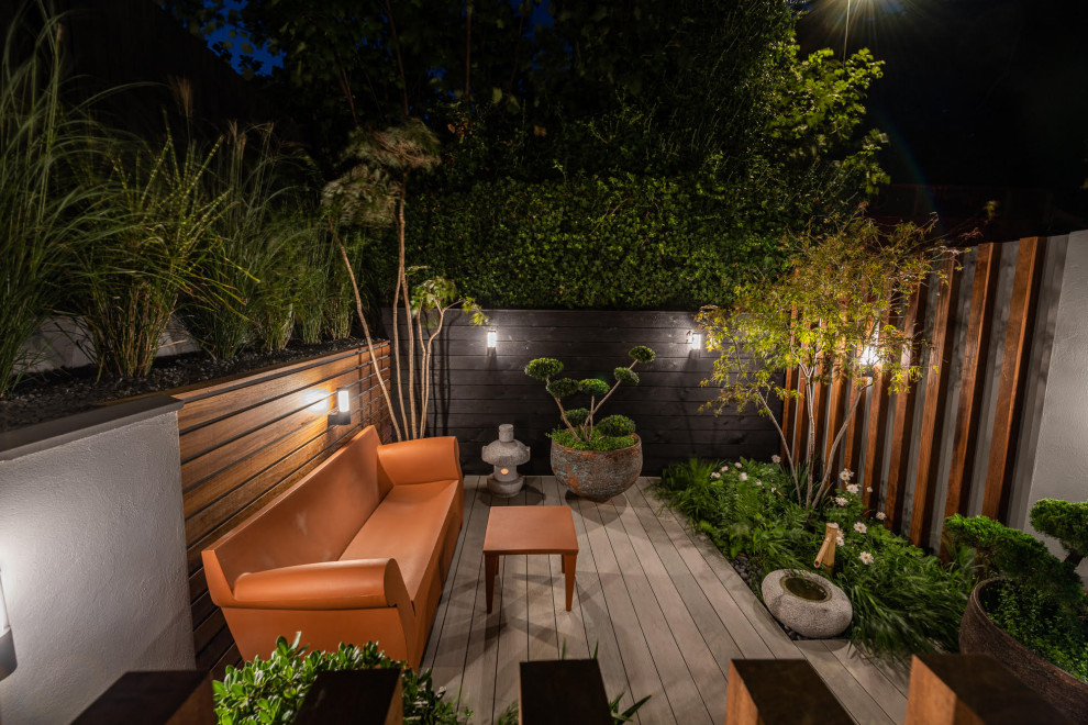 Small contemporary courtyard formal partial sun garden wall for spring in London with decking.