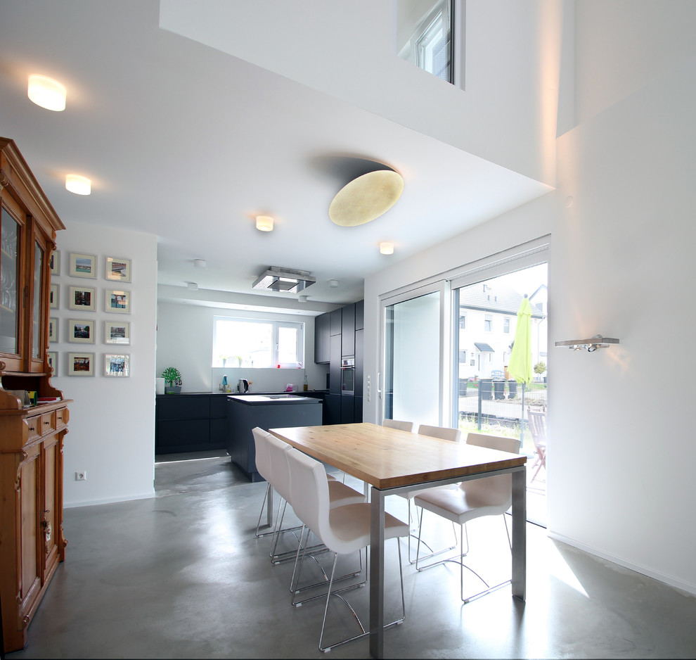 Offenes Modernes Esszimmer mit Betonboden und weißer Wandfarbe in Bonn