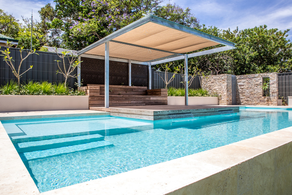 This is an example of a large contemporary backyard rectangular aboveground pool in Perth with a water feature and natural stone pavers.