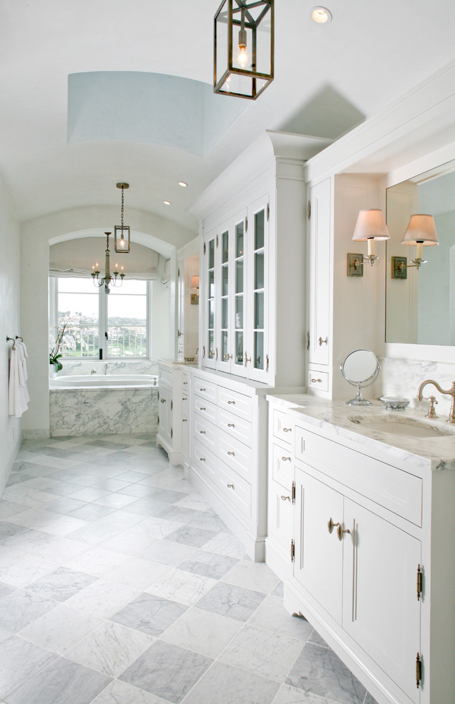 Photo of a beach style master bathroom in Orange County with an undermount sink, recessed-panel cabinets, white cabinets, white walls and a drop-in tub.