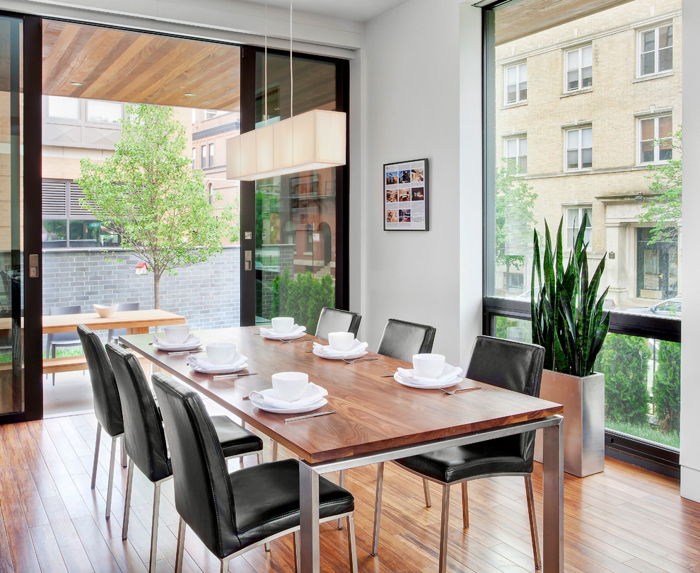 This is an example of a contemporary dining room in Chicago with white walls and medium hardwood floors.