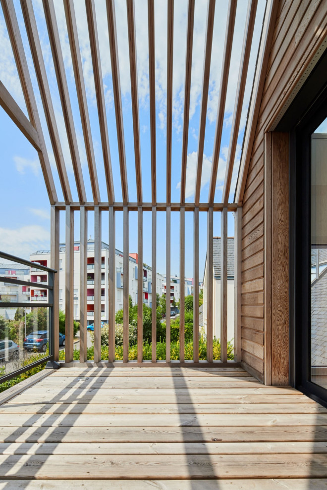 Idée de décoration pour une terrasse au premier étage design de taille moyenne avec des solutions pour vis-à-vis, une cour, une pergola et un garde-corps en bois.