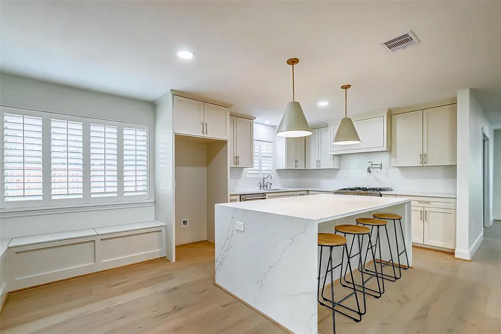 Example of a large light wood floor and beige floor eat-in kitchen design with quartzite countertops, marble backsplash and stainless steel appliances