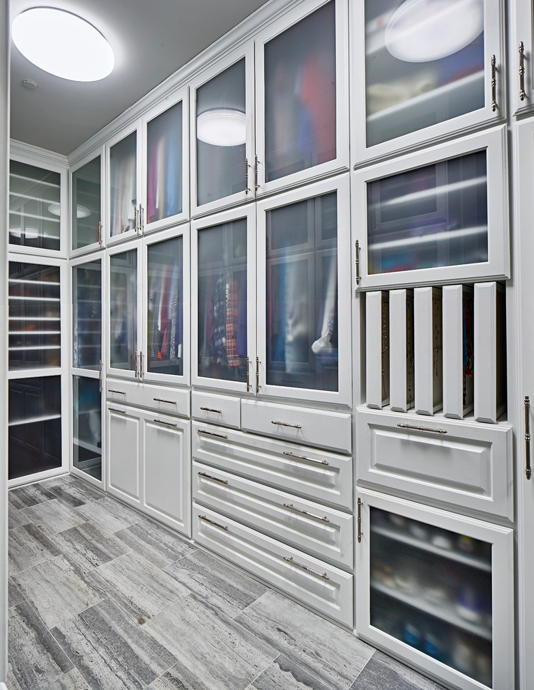 Photo of a large contemporary gender-neutral dressing room in Dallas with raised-panel cabinets, white cabinets, grey floor and limestone floors.