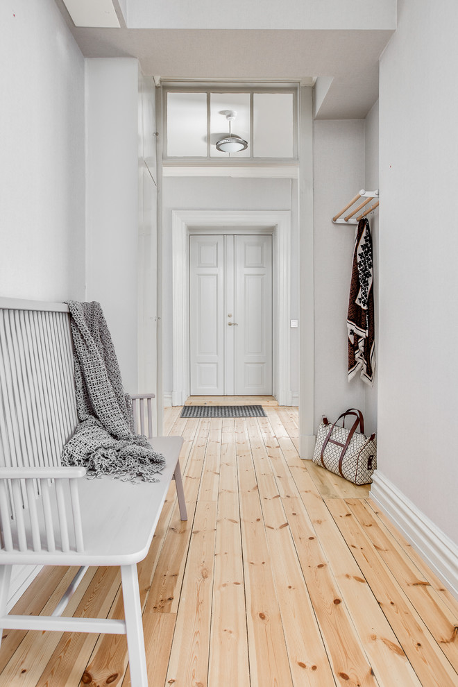 Photo of a scandinavian hallway in Gothenburg with white walls and light hardwood floors.