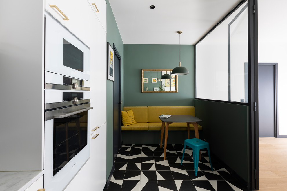 This is an example of a mid-sized contemporary u-shaped kitchen in Paris with a single-bowl sink, white cabinets, green splashback, white appliances, porcelain floors, black floor and white benchtop.