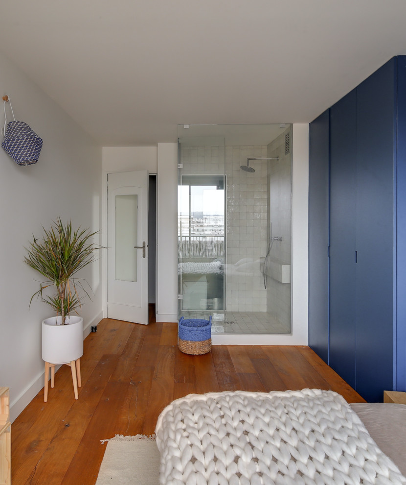 Idées déco pour une grande chambre parentale contemporaine avec un mur bleu, un sol en bois brun, aucune cheminée et un sol marron.