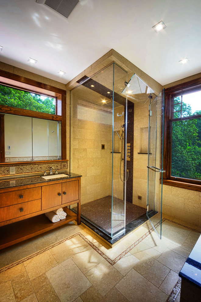 Design ideas for a large modern bathroom in New York with an undermount sink, furniture-like cabinets, medium wood cabinets, marble benchtops, an undermount tub, a two-piece toilet, brown tile, stone tile, brown walls and limestone floors.