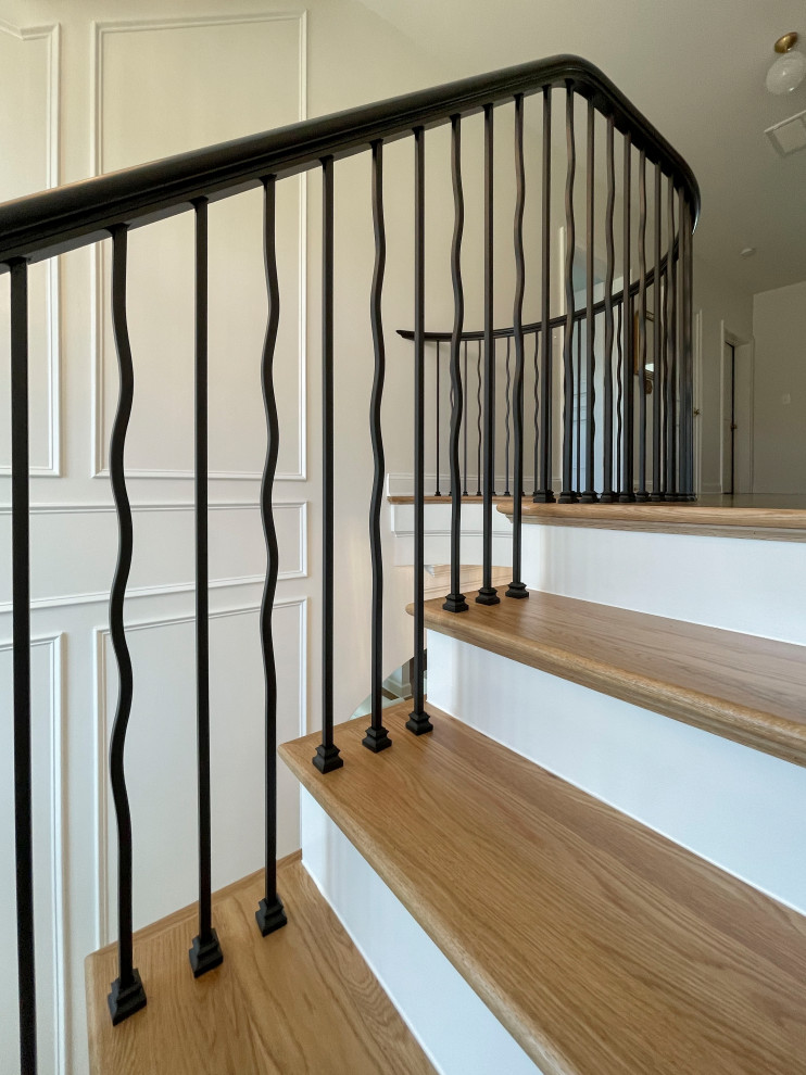Diseño de escalera suspendida clásica renovada grande con escalones de madera, contrahuellas de madera pintada, barandilla de varios materiales y boiserie