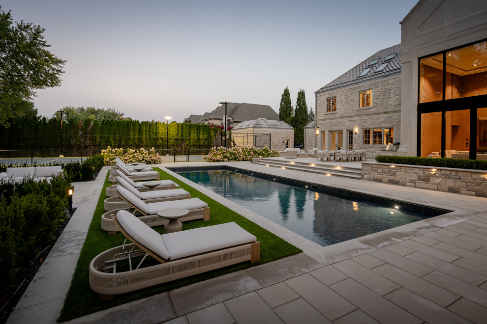 Cette photo montre un grand piscine avec aménagement paysager arrière tendance rectangle avec des pavés en béton.
