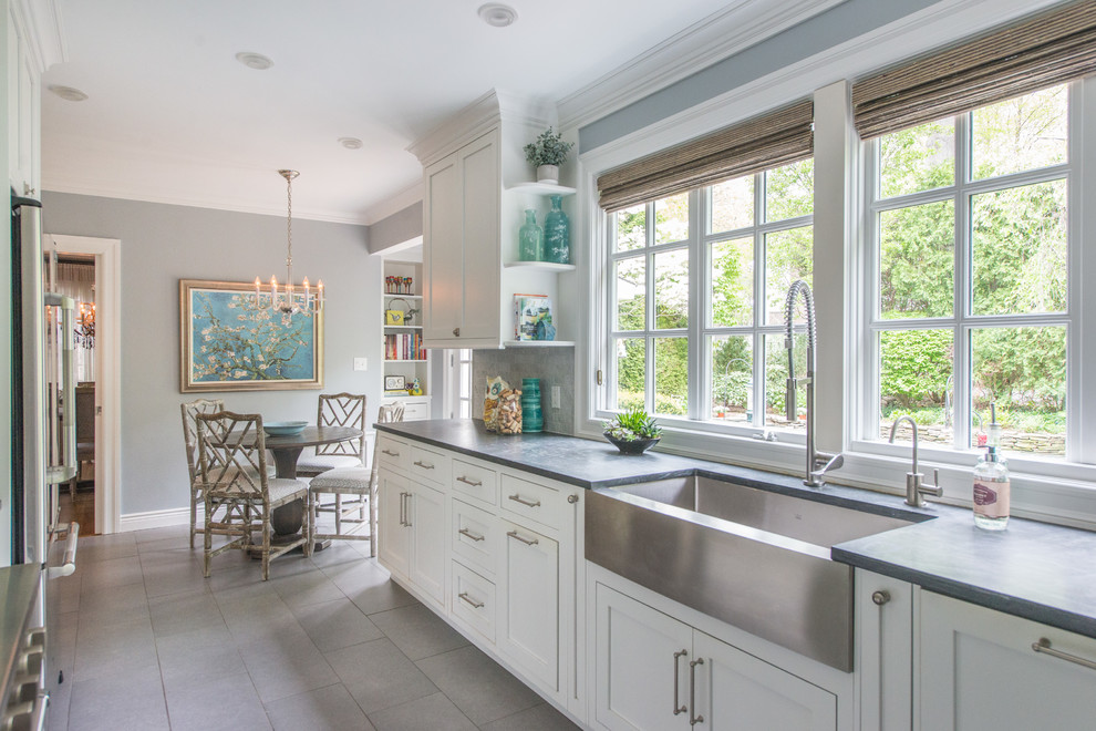Inspiration for a mid-sized transitional u-shaped separate kitchen in New York with a farmhouse sink, recessed-panel cabinets, white cabinets, grey splashback, marble splashback, stainless steel appliances, slate floors, no island and grey floor.