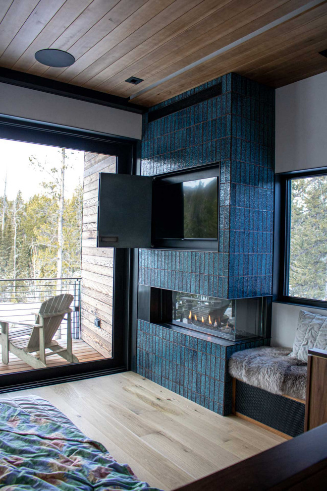 Inspiration för små moderna huvudsovrum, med vita väggar, ljust trägolv, en öppen hörnspis och en spiselkrans i trä