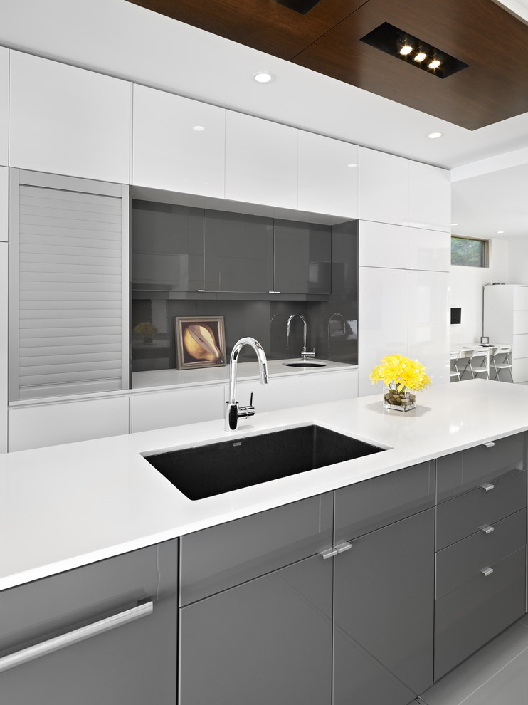 Modern kitchen in Edmonton with flat-panel cabinets, grey cabinets, grey splashback and glass sheet splashback.