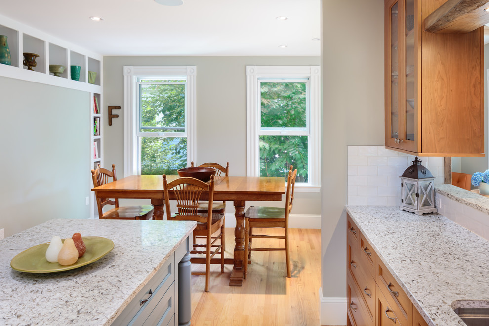 Inspiration for a mid-sized transitional u-shaped eat-in kitchen in Boston with an undermount sink, shaker cabinets, medium wood cabinets, granite benchtops, white splashback, subway tile splashback, stainless steel appliances, light hardwood floors and with island.