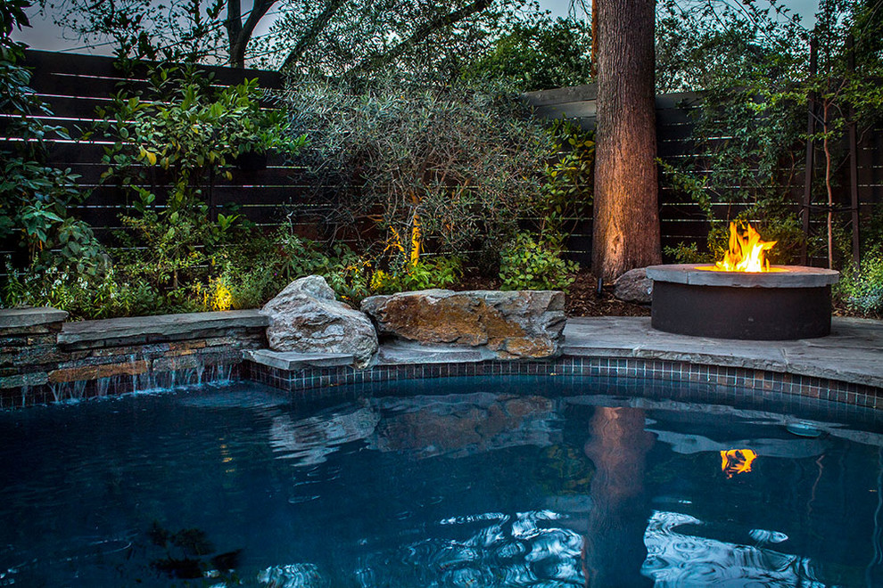 Photo of a large modern backyard kidney-shaped pool in Los Angeles with natural stone pavers.