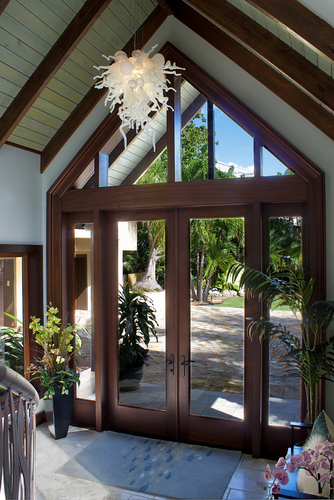 Inspiration for a large tropical front door in Miami with a double front door, a dark wood front door, blue walls, beige floor and marble floors.
