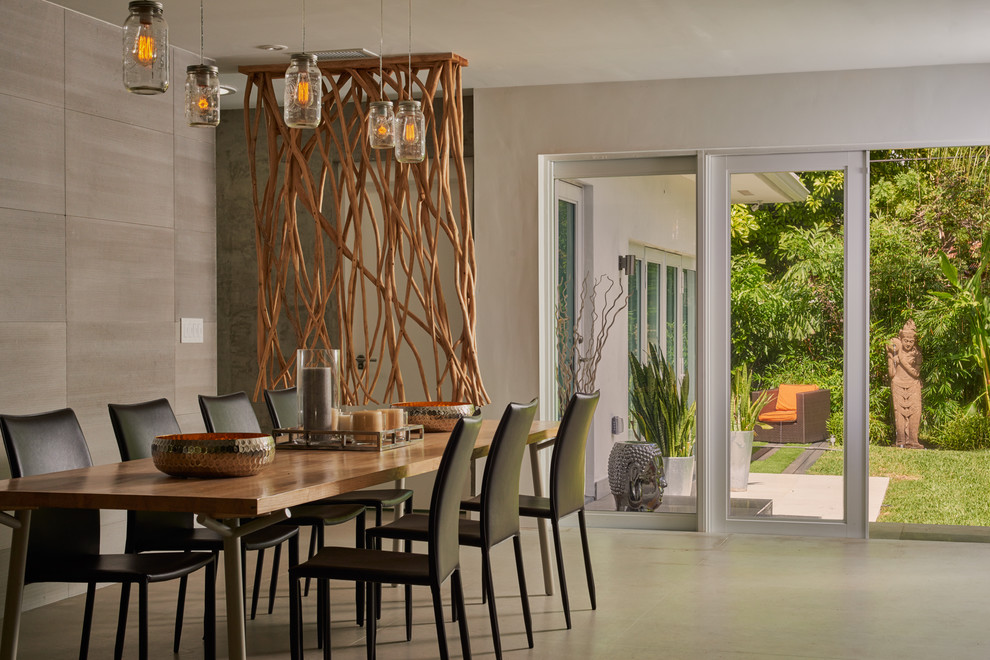 Photo of a large modern separate dining room in Miami with white walls, concrete floors, no fireplace and grey floor.