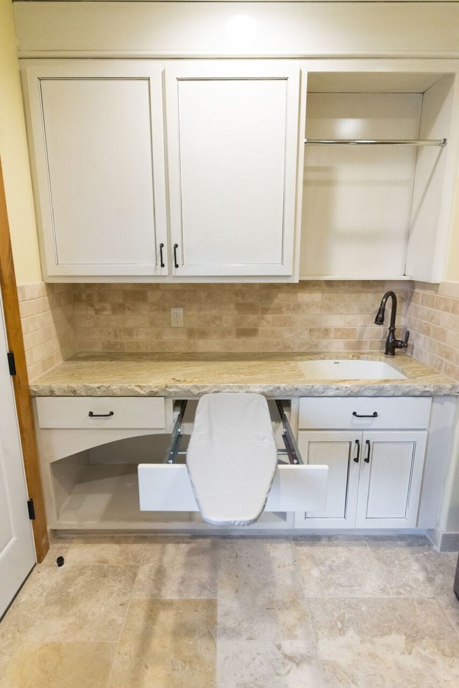 Photo of a mid-sized country utility room in Orange County with an undermount sink, white cabinets, granite benchtops, yellow walls, travertine floors, beige floor and recessed-panel cabinets.