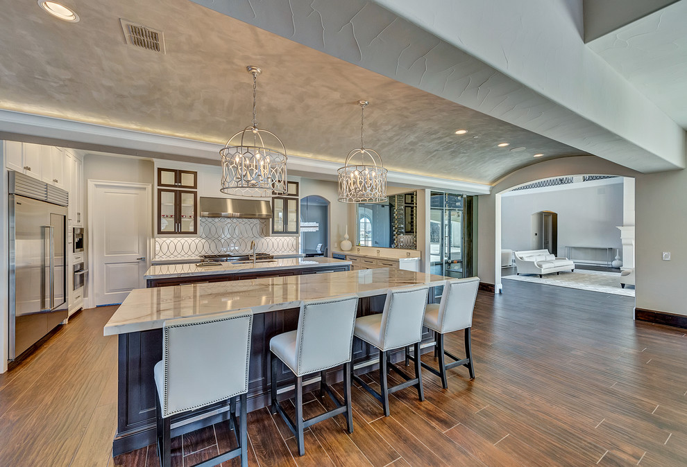 Inspiration for a huge transitional u-shaped ceramic tile and brown floor eat-in kitchen remodel in Orange County with an undermount sink, shaker cabinets, white cabinets, marble countertops, white backsplash, marble backsplash, stainless steel appliances and two islands