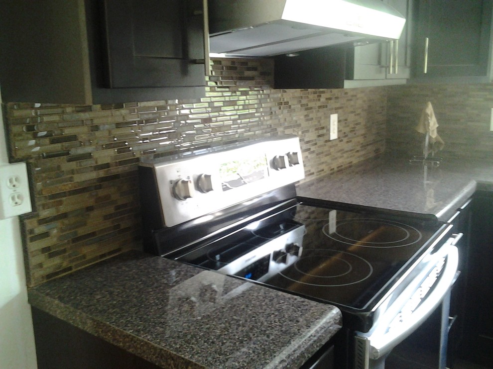 Inspiration for a mid-sized transitional l-shaped porcelain tile enclosed kitchen remodel in Indianapolis with a drop-in sink, shaker cabinets, dark wood cabinets, granite countertops, brown backsplash, glass tile backsplash, stainless steel appliances and no island