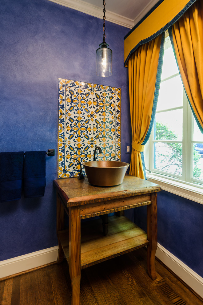 This is an example of a mediterranean powder room in Richmond with a vessel sink, open cabinets, multi-coloured tile, blue walls and dark hardwood floors.