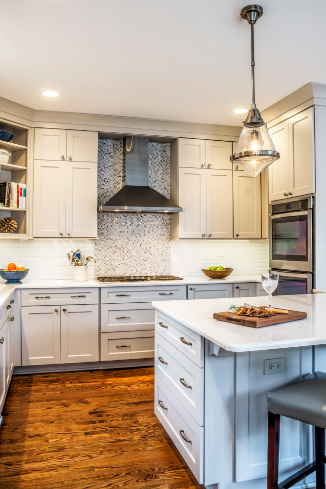Mid-sized transitional u-shaped medium tone wood floor eat-in kitchen photo in Chicago with an undermount sink, shaker cabinets, gray cabinets, quartz countertops, white backsplash, stone tile backsplash, stainless steel appliances, a peninsula and white countertops
