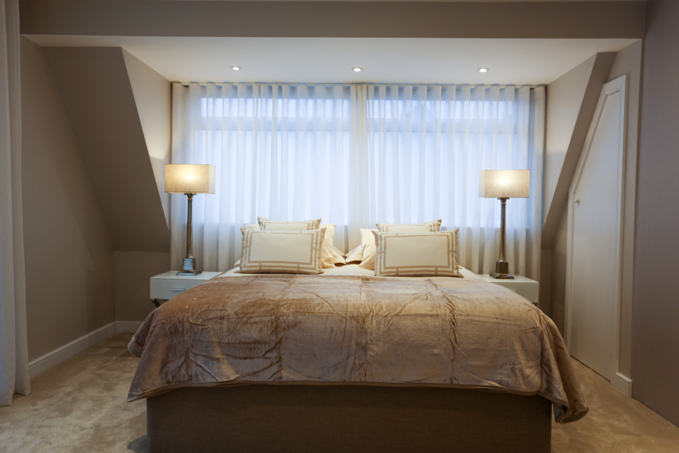 Large contemporary master bedroom in Hertfordshire with beige walls, carpet and beige floors.