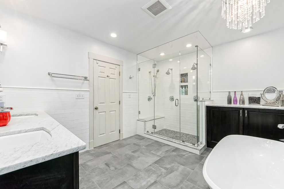 Design ideas for a mid-sized contemporary bathroom in Columbus with recessed-panel cabinets, black cabinets, a claw-foot tub, a corner shower, white tile, subway tile, grey walls, porcelain floors, an undermount sink, grey floor and a hinged shower door.