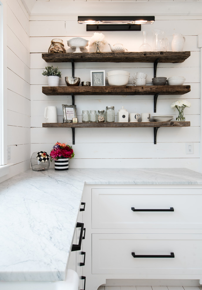 Photo of a mid-sized beach style u-shaped separate kitchen in New York with a farmhouse sink, shaker cabinets, white cabinets, marble benchtops, white splashback, timber splashback, panelled appliances, painted wood floors, no island and white floor.