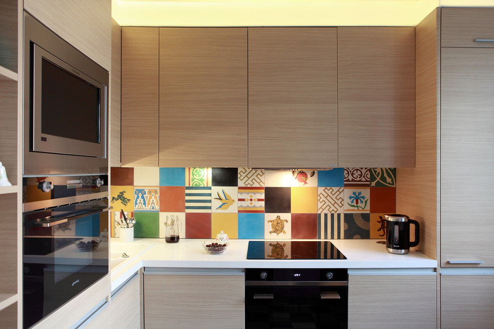 This is an example of a small contemporary l-shaped separate kitchen in Moscow with flat-panel cabinets, light wood cabinets, multi-coloured splashback, black appliances, no island and cement tile splashback.
