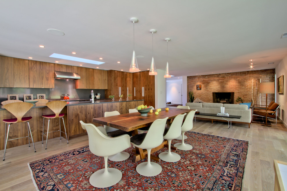 Inspiration for a mid-sized midcentury open plan dining in Indianapolis with white walls, light hardwood floors, a standard fireplace, a brick fireplace surround and beige floor.