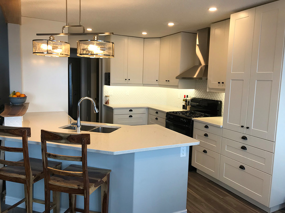 Example of a mid-sized transitional l-shaped medium tone wood floor and brown floor eat-in kitchen design in Calgary with a double-bowl sink, recessed-panel cabinets, white cabinets, quartzite countertops, white backsplash, stainless steel appliances, white countertops, ceramic backsplash and an island
