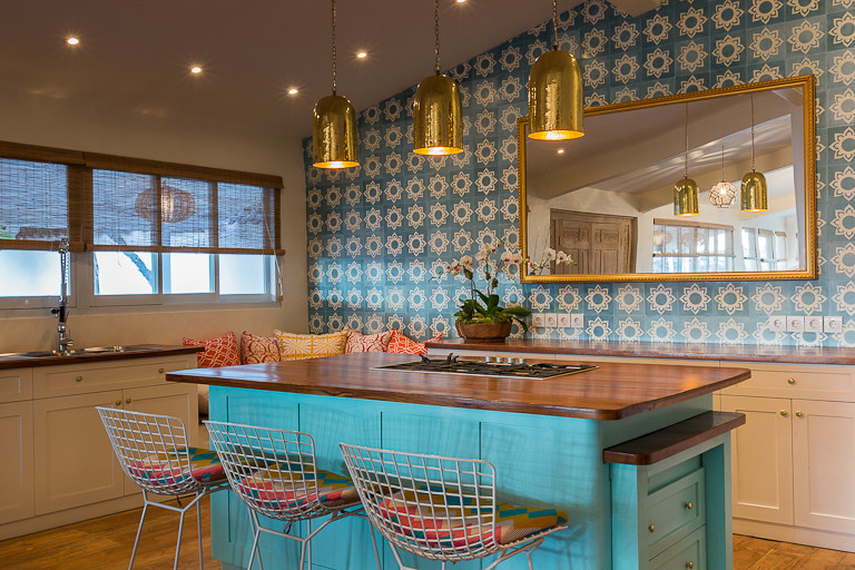 Photo of a large eclectic l-shaped open plan kitchen in Other with a drop-in sink, shaker cabinets, white cabinets, wood benchtops, blue splashback, cement tile splashback, stainless steel appliances, medium hardwood floors and with island.