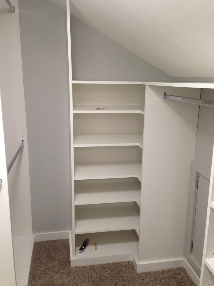 Small transitional gender-neutral walk-in wardrobe in Los Angeles with flat-panel cabinets, white cabinets and carpet.
