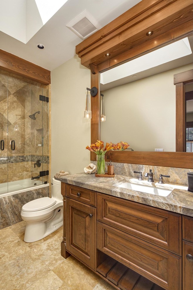 Country bathroom in Other with an undermount sink, raised-panel cabinets, medium wood cabinets, an alcove tub, a shower/bathtub combo, brown tile and beige walls.