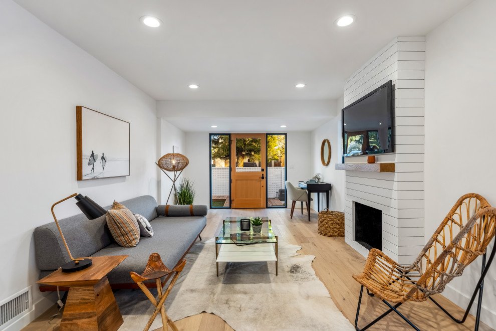 Immagine di un soggiorno design aperto con pareti bianche, parquet chiaro, camino classico, TV a parete e pavimento beige