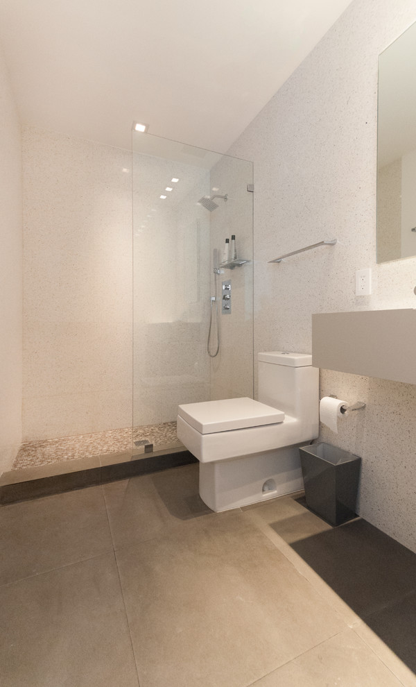 Photo of a small contemporary 3/4 bathroom in Miami with a wall-mount sink, an open shower, a one-piece toilet, beige tile, stone slab, beige walls and limestone floors.