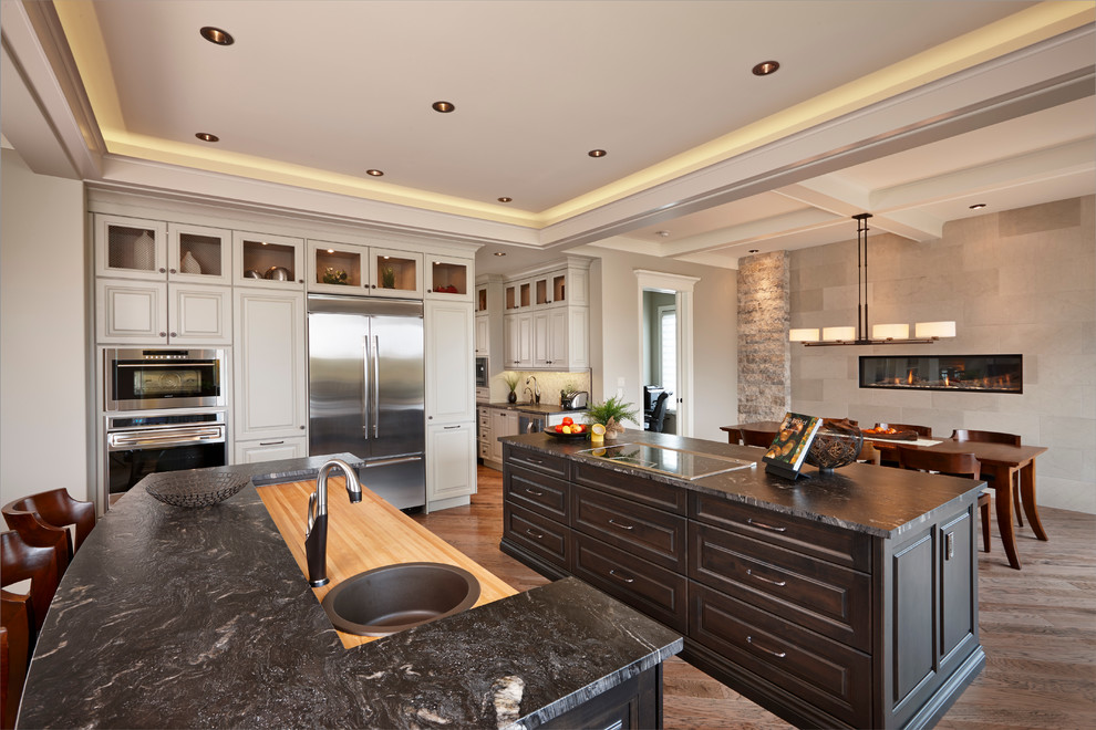 Design ideas for a transitional galley open plan kitchen in Calgary with an undermount sink, beaded inset cabinets, white cabinets, granite benchtops, multi-coloured splashback, mosaic tile splashback, stainless steel appliances, medium hardwood floors and multiple islands.
