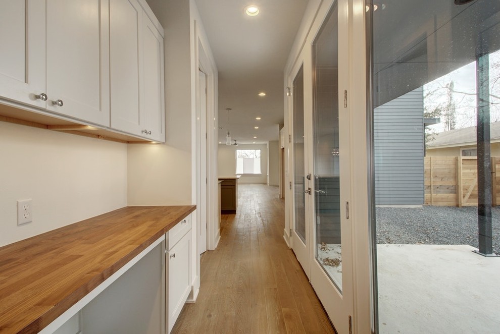 This is an example of a mid-sized midcentury hallway in Austin with beige walls, dark hardwood floors and brown floor.