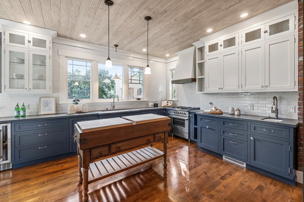 Inspiration for a large arts and crafts u-shaped eat-in kitchen in San Francisco with an undermount sink, beaded inset cabinets, blue cabinets, quartz benchtops, white splashback, brick splashback, stainless steel appliances, medium hardwood floors, with island, brown floor, black benchtop and timber.