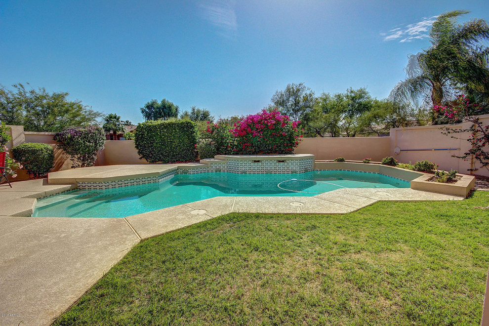 Mid-sized mediterranean backyard custom-shaped pool in Phoenix with concrete pavers.