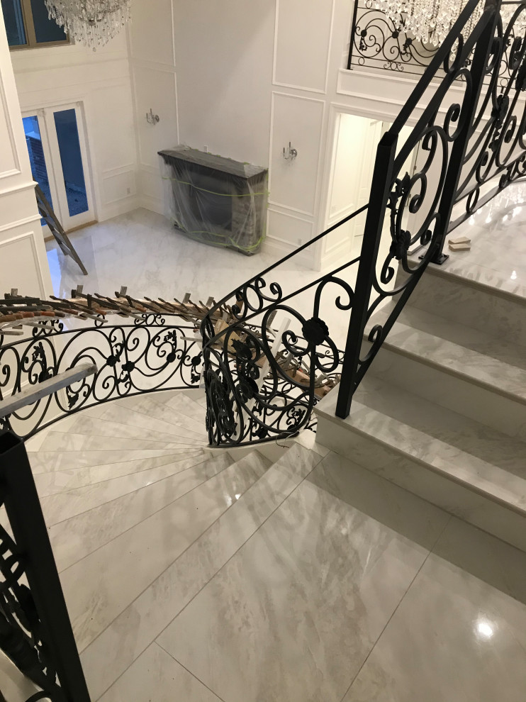 Inredning av en klassisk mycket stor svängd trappa i marmor, med räcke i metall och sättsteg i marmor